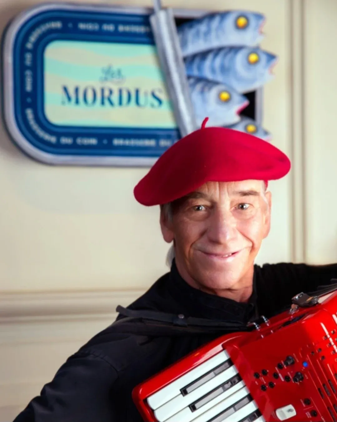 Accordéoniste coiffé d’un béret rouge, tenant un accordéon rouge aux Mordus.